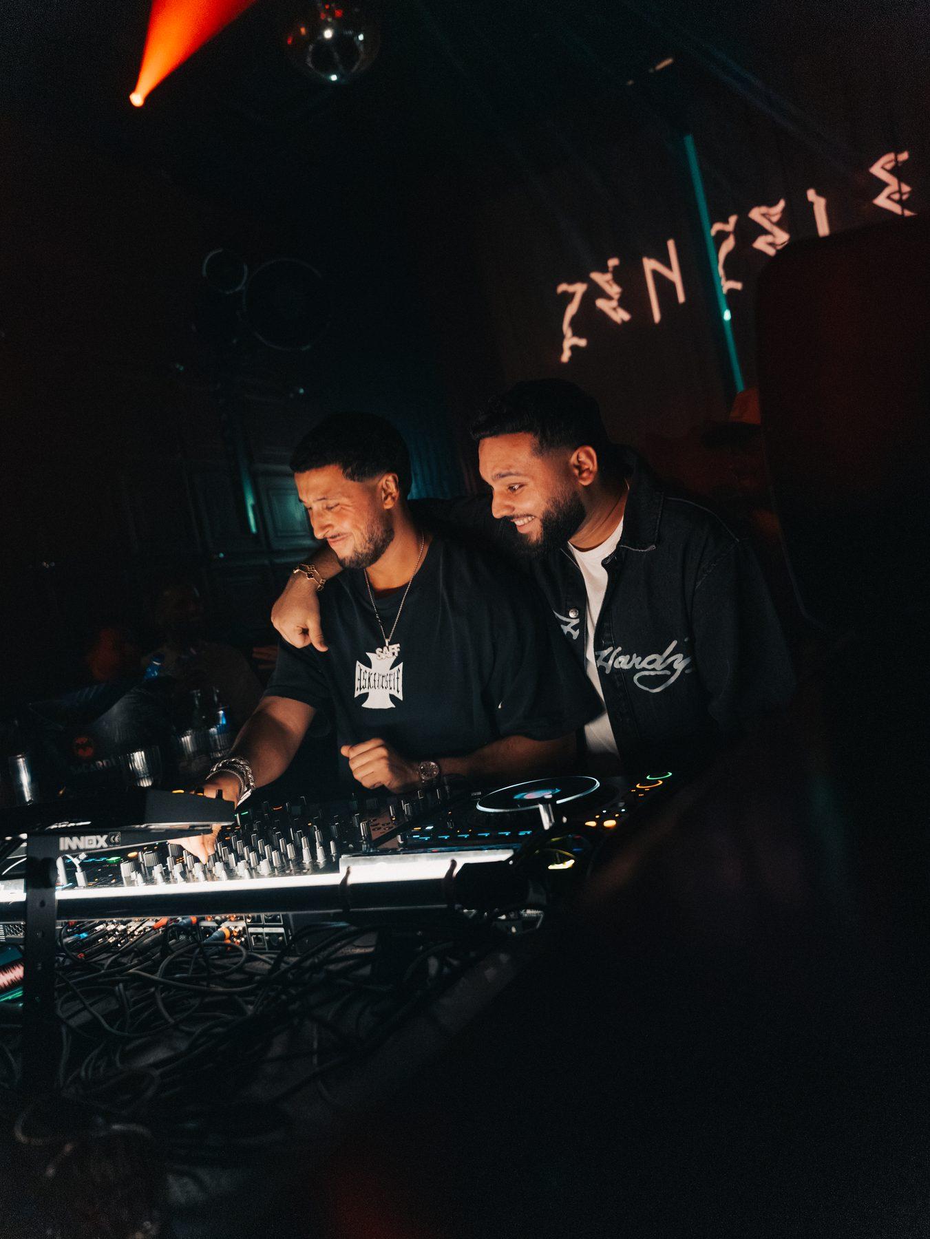 Saffou in the DJ booth under the glowing ZENZELE sign